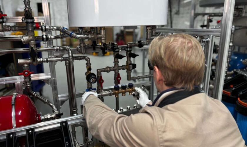 Engineer working on industrial pipe system in a factory for heating and production adjustment.