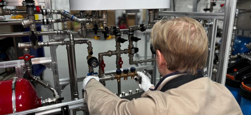 Engineer working on industrial pipe system in a factory for heating and production adjustment.