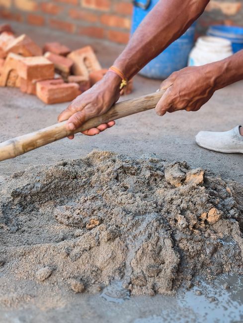 Hands mixing mortar for bricklaying in a construction setting. Manual labor.