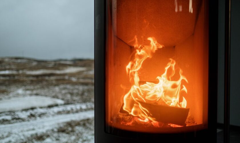 Indoor fireplace with burning flame creating warmth against snowy winter outdoors.