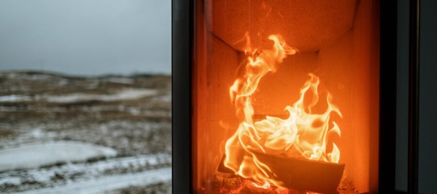 Indoor fireplace with burning flame creating warmth against snowy winter outdoors.