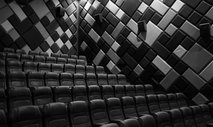 Interior of an empty cinema hall with leather seats and acoustic walls in grayscale.