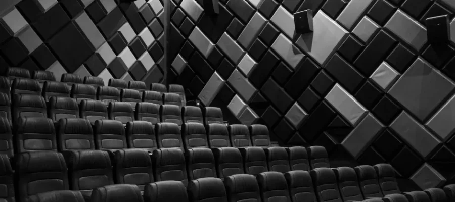 Interior of an empty cinema hall with leather seats and acoustic walls in grayscale.