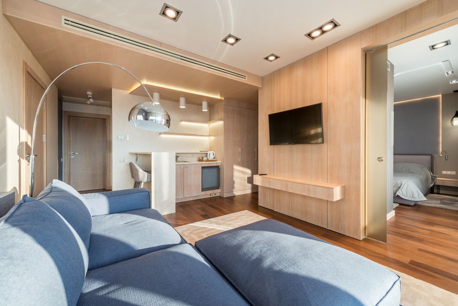 Interior of modern studio apartment comfortable with sofa and kitchen zone separating from bedroom with sliding doors