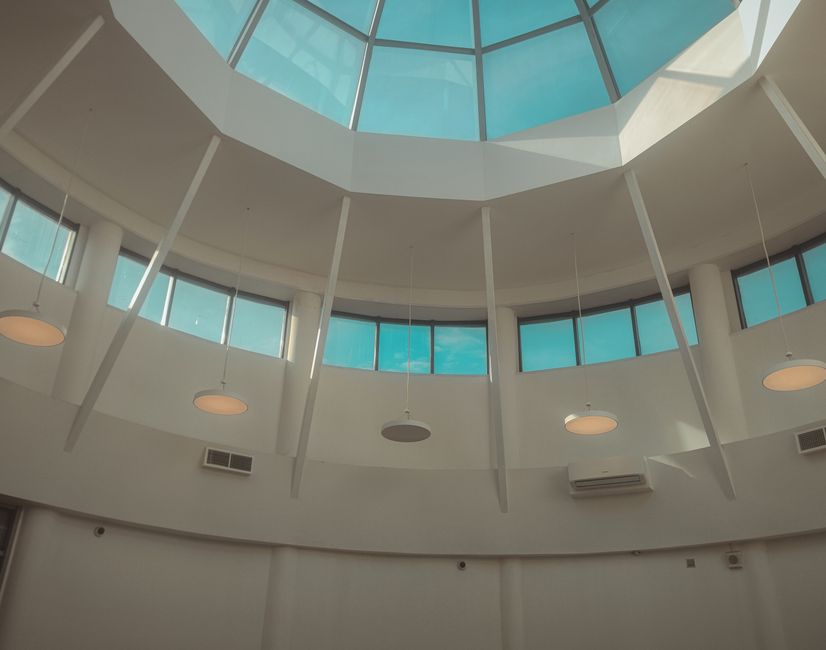 Interior view of a modern dome ceiling with a circular skylight and suspended lights.
