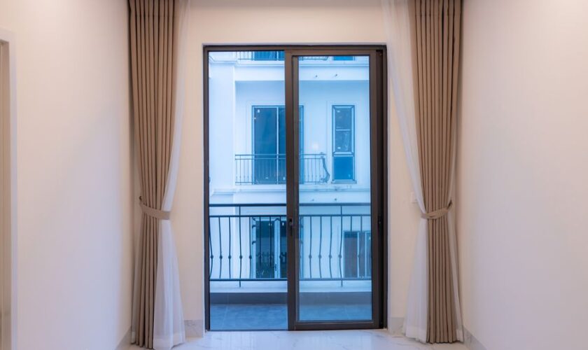 Interior view of a modern room featuring a large sliding glass door with elegant curtains.