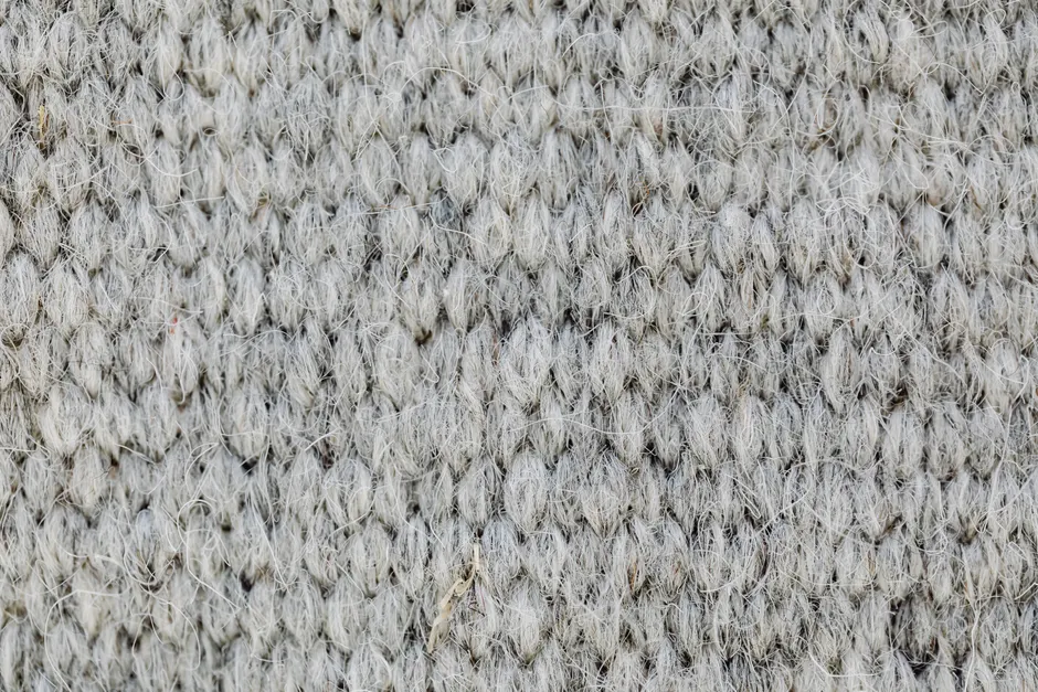 Macro of a grey wool knitted fabric texture showcasing intricate patterns and fibers.