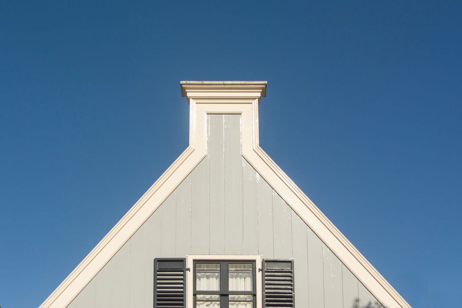 Minimalist architectural detail of a gable roof against a clear blue sky.