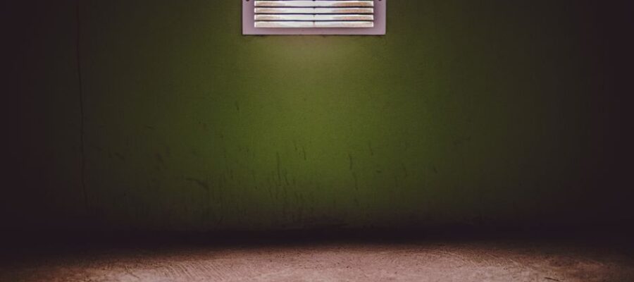 Moody room with a ventilation grate on a textured green wall.