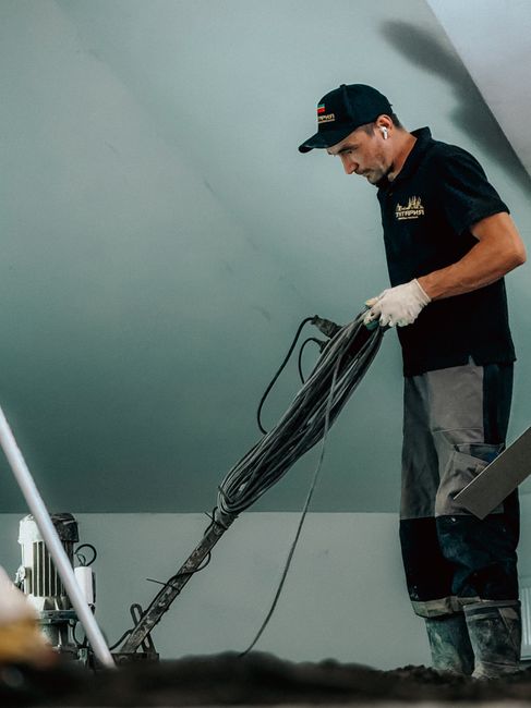 Professional construction worker using machinery indoors for flooring or renovation work.