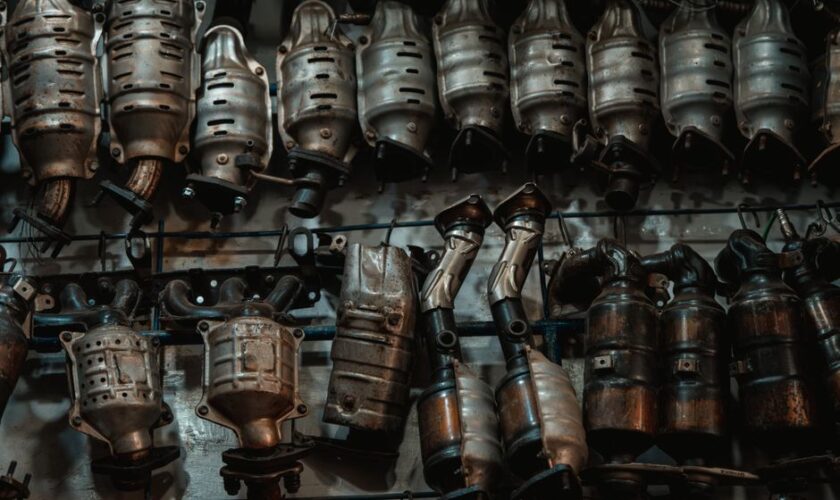 Rows of used catalytic converters in an automotive workshop setting.