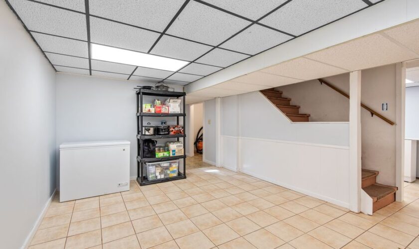 Spacious basement featuring tiled floor, storage shelves, and staircase in a modern setting.