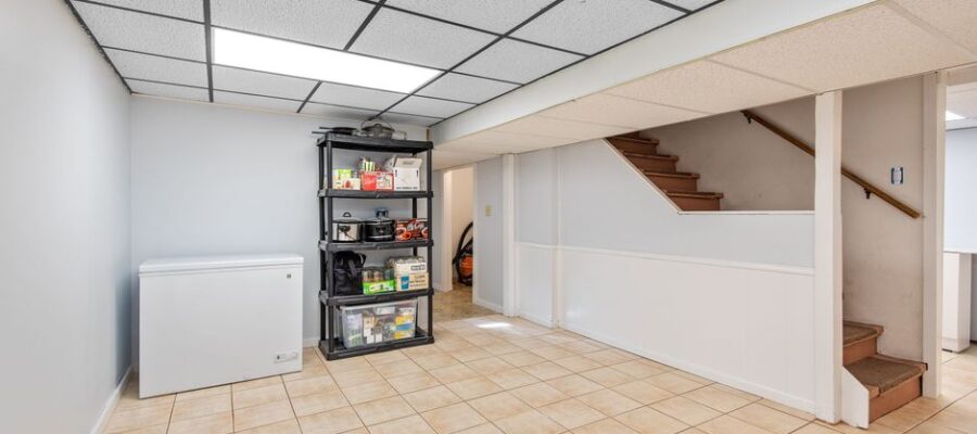 Spacious basement featuring tiled floor, storage shelves, and staircase in a modern setting.