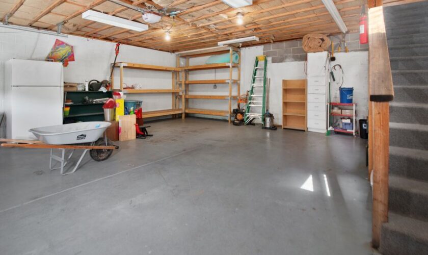Spacious garage interior with storage shelves, tools, and a wheelbarrow, ideal for home organization.