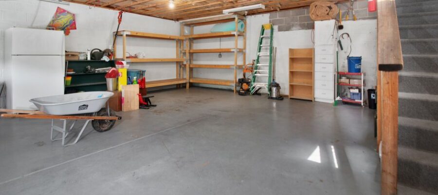 Spacious garage interior with storage shelves, tools, and a wheelbarrow, ideal for home organization.