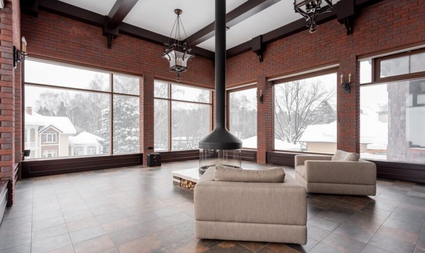 Spacious living room with armchairs and fireplace overlooking a snowy landscape.