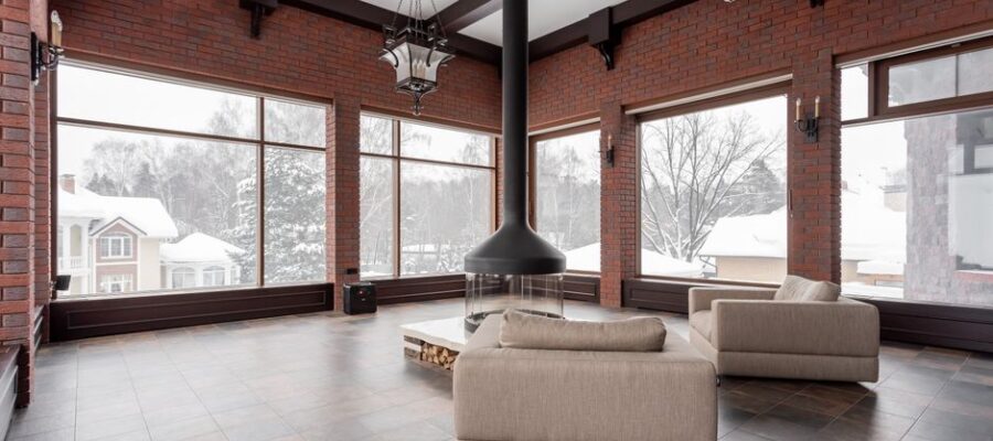 Spacious living room with armchairs and fireplace overlooking a snowy landscape.