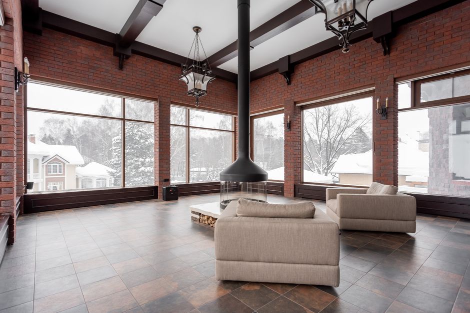 Spacious living room with armchairs and fireplace overlooking a snowy landscape.