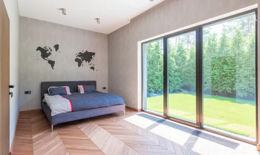 Stylish minimalist bedroom with a bed and sliding glass doors overlooking a garden.