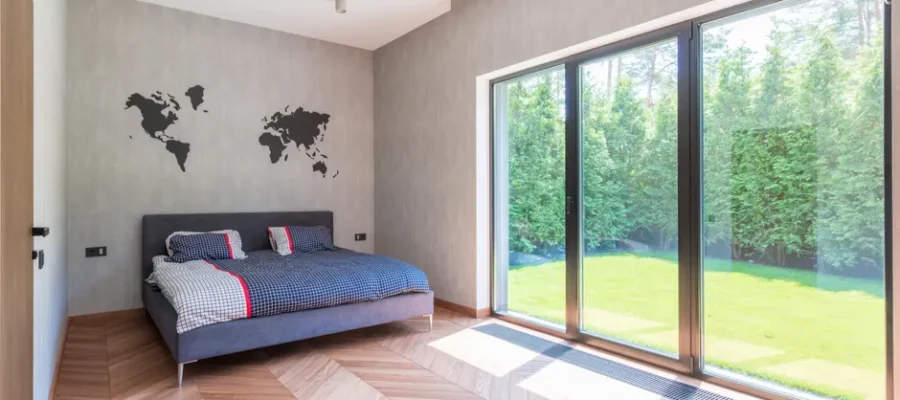Stylish minimalist bedroom with a bed and sliding glass doors overlooking a garden.