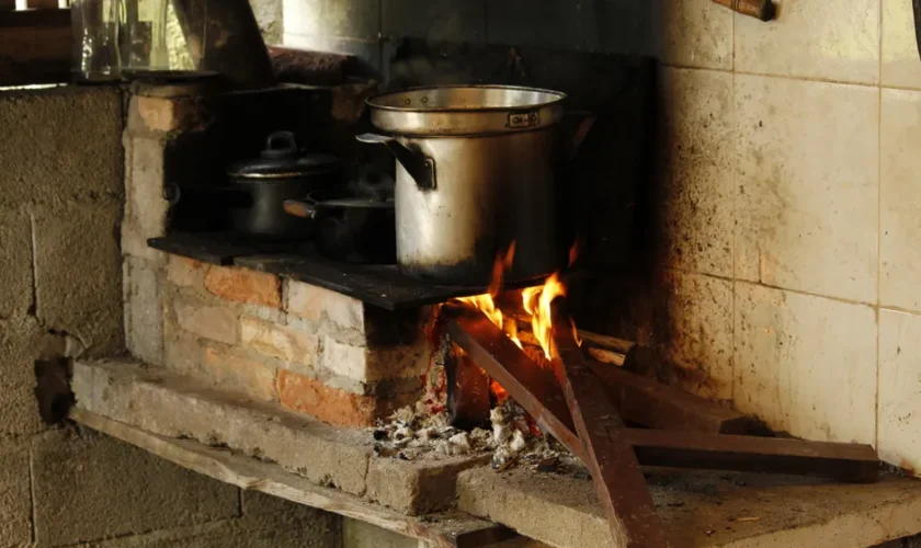Traditional cooking setup with a wood fire stove in a rustic kitchen setting.