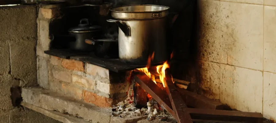 Traditional cooking setup with a wood fire stove in a rustic kitchen setting.