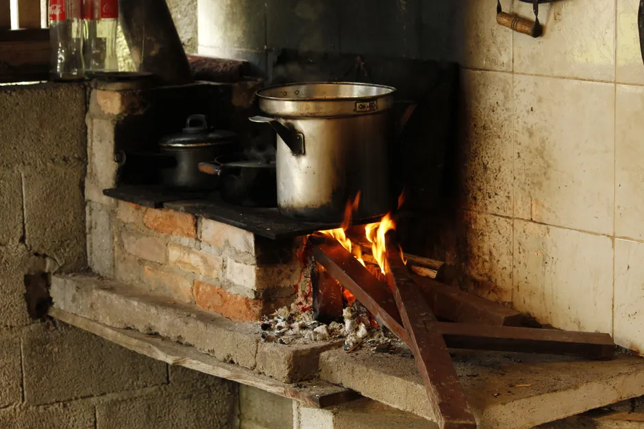 Traditional cooking setup with a wood fire stove in a rustic kitchen setting.