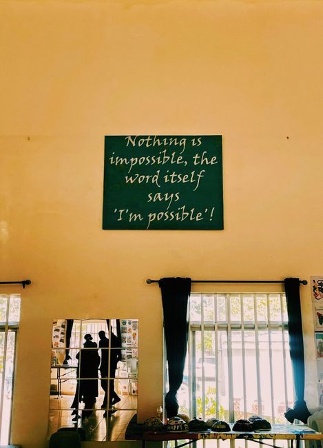 Wall art with motivational quote in bright room with window reflections.