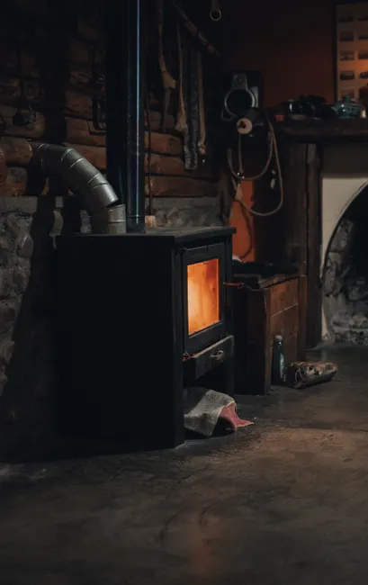 Warm and inviting indoor scene featuring a rustic wood-burning stove against a brick wall.