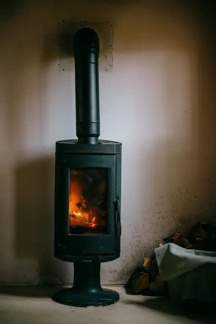 Warm and inviting rustic wood stove in a simple French interior setting.