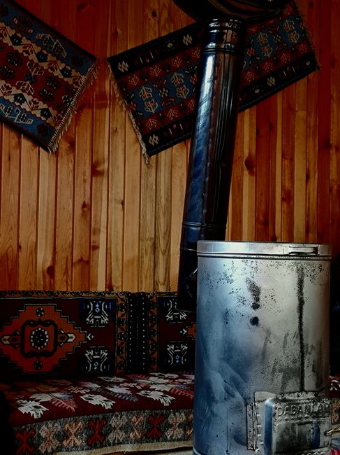 Warm, rustic interior featuring traditional patterned carpets and a vintage wood-burning stove.