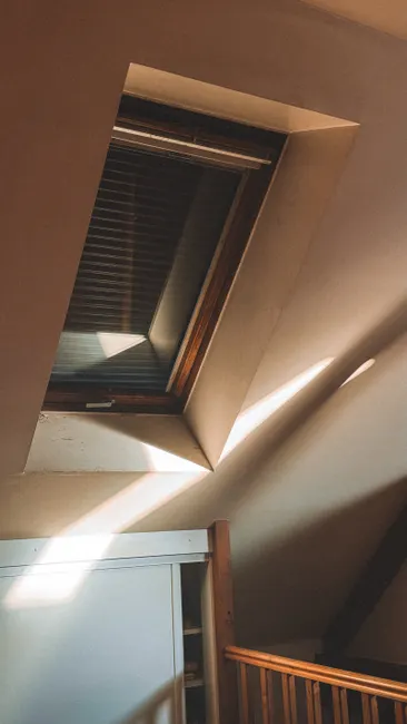 Warm sunlight casting through an attic window, illuminating wooden interior details.