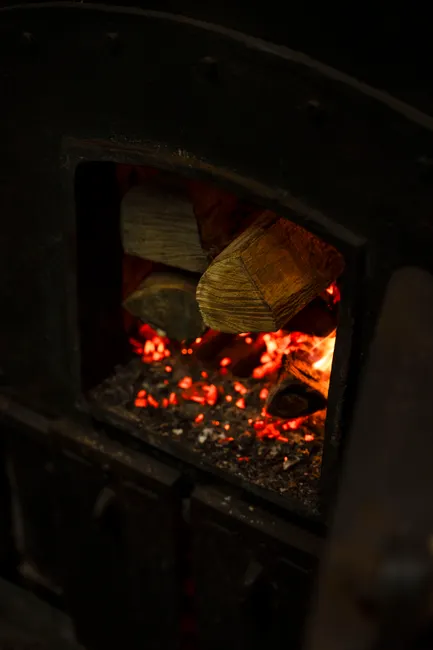 Warm wood logs burning in an antique stove, creating a cozy ambiance.