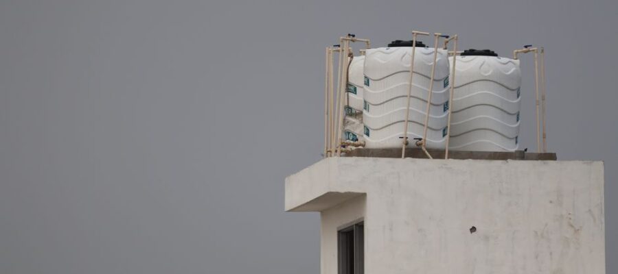White water tanks on a rooftop with architectural design, under a gray sky.