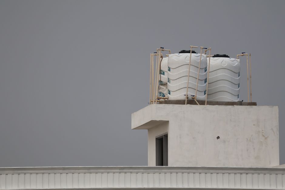 White water tanks on a rooftop with architectural design, under a gray sky.