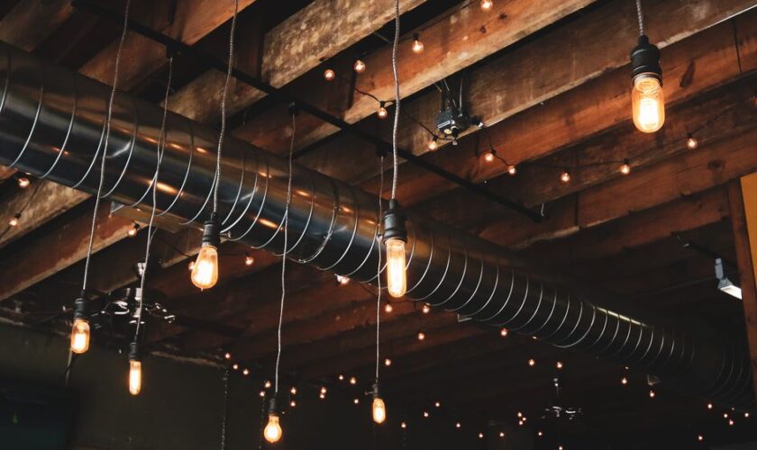Wooden ceiling featuring industrial hanging lights and exposed ductwork for a modern rustic look.