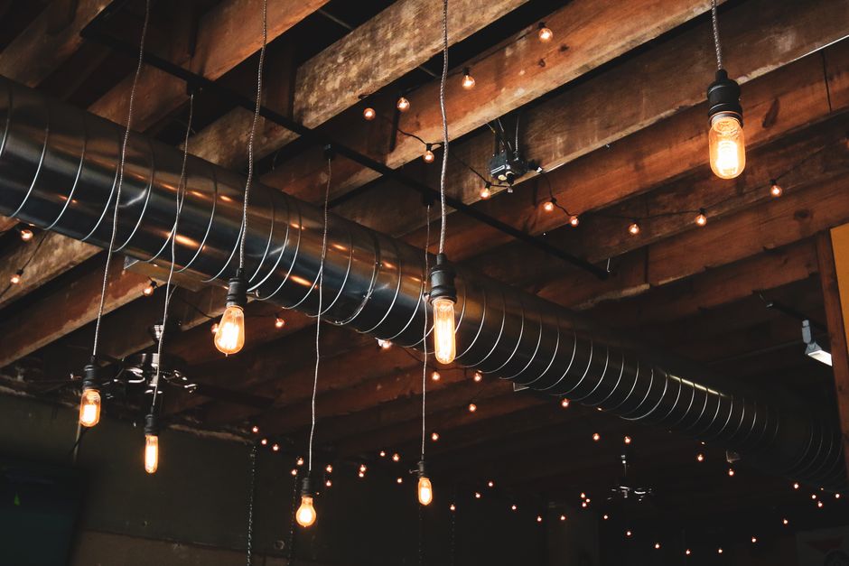 Wooden ceiling featuring industrial hanging lights and exposed ductwork for a modern rustic look.