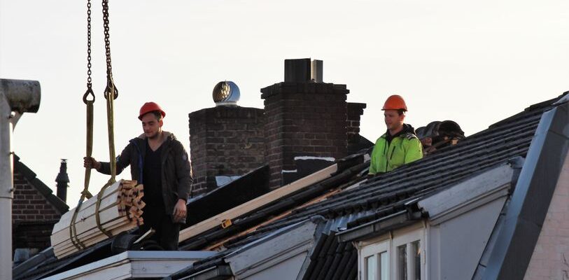 Workers operate on a rooftop under construction in the Netherlands, showcasing teamwork and safety.