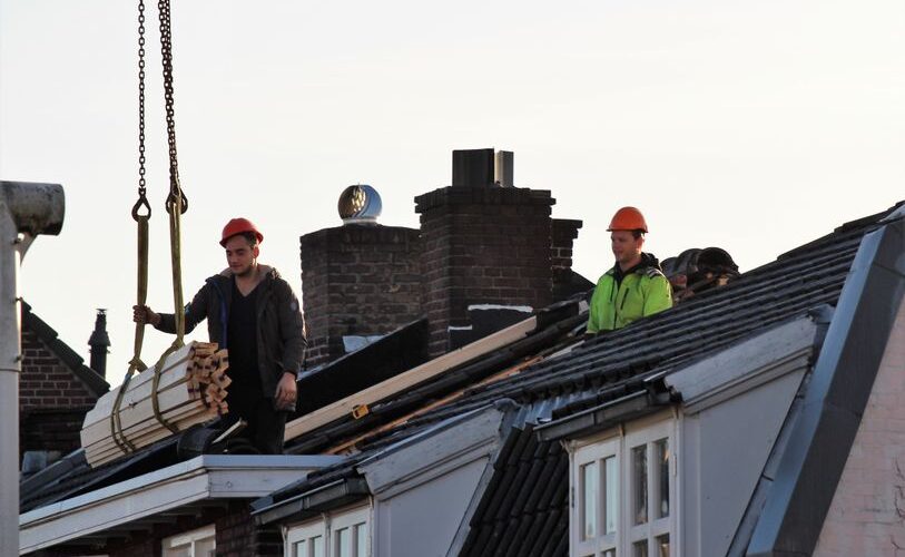 Workers operate on a rooftop under construction in the Netherlands, showcasing teamwork and safety.